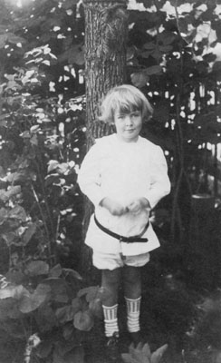 Young boy standing by tree