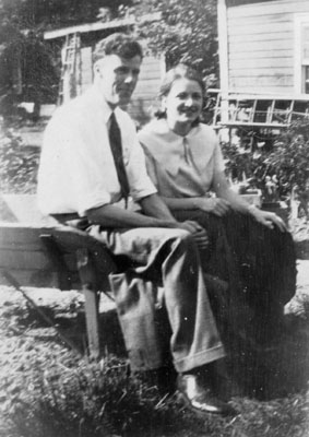 Man and woman seated on wheel barrow