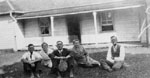 Group sitting on grass in front of house