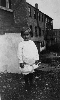 Young child posed in front of basement of building