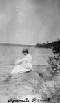 Lady sitting on a rock by a lake