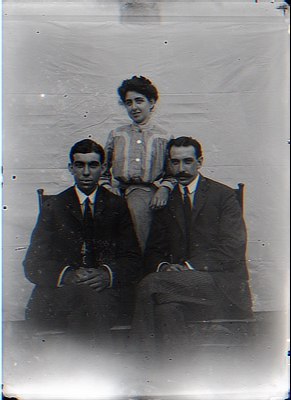 Woman Standing Behind 2 Seated Men in Posed Photo