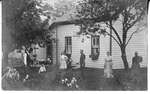 Unknown family playing croquet outside of a house