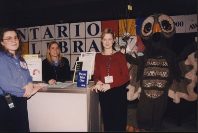 Maria Ferraro (Ripley), Katerina Podolak, and Shannon Polk with Owl Magazine's mascot at the Super Conference 2000 exhibits.