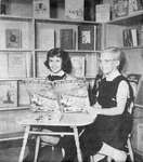 Two Girls pose with a book in the new Children's Library