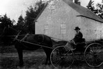 Mr. Crew - old Cavendish mailman, sitting in a buggy in front of Cavendish Homestead, ca.1890's.  Cavendish, P.E.I.