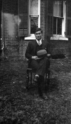 Chester with hat on knee sitting in garden, Norval, ON.