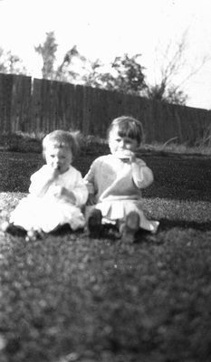 Chester with another young child sitting on the grass.