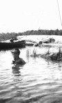 Stuart sitting in water beside a canoe, Leaskdale, ON.