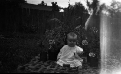 Stuart as a baby sitting on a rug in the garden, Leaskdale, ON.