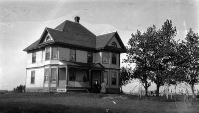 Three (unidentified) figures in front of house, PEI.