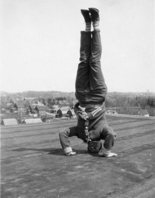 Waterloo College student doing a headstand on the roof of Willison Hall