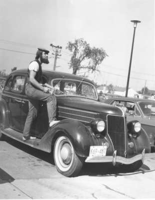 Male Waterloo Lutheran University student standing on car