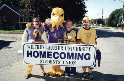 Three students and the Hawk mascot at Homecoming 2001, Wilfrid Laurier University