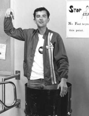 Male Waterloo Lutheran University student standing in a garbage can