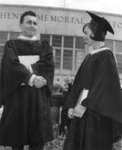 Two Waterloo Lutheran University graduates standing in front of the Kitchener Memorial Auditorium