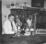 Bruce Kelley and Wilfred Myra in a science laboratory