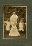 Priest standing with three girls holding flowers