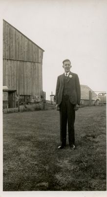 A young man standing in front of a barn