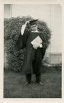 A young man wearing a graduation cap and gown holding a diploma