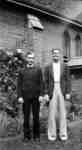 Rev. Patrick Moore and unidentified person standing in front of St. John the Evangelist Roman Catholic Church, c.1936