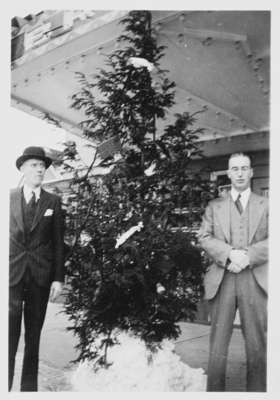 William G. Goodman and John G. Strathy pose with their Christmas tree in front of Brock Theatre