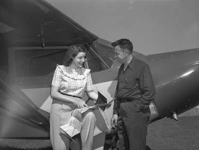 Unidentified woman and man next to Piper PA12 aircraft