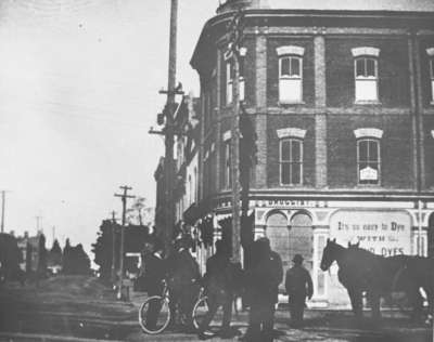 Person with Bicycle and horses outside Allin's Drug Store