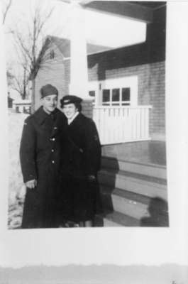 Photograph of an unidentified man and woman standing in front of a building