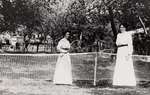 Two women playing lawn tennis