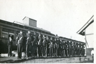 Soldiers lined up beside train with rifles in hand