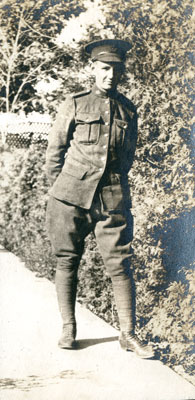 One soldier standing by a hedge