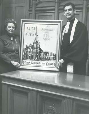 Rev. Cam Taylor (right) with Dorothy Adams (left) with her gift to the congregation of a petitepoint design of Knox Church for the 150th anniversary of the church.