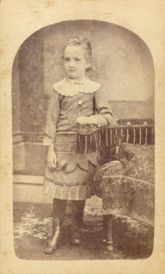 Little Girl Standing Next to an Elaborate Chair