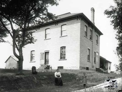 Woman and Child in Front of Rural Brick Home, c. 1902-1906