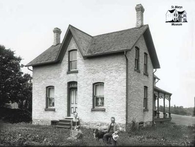 Man, Woman and Dog with Brick House, c. 1902-1906