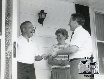 Two Men and a Woman in Front of House