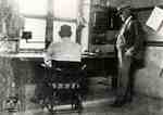 W. A. Kingsland watching William Jacobi at desk alleged to have been used by Thomas Edison
