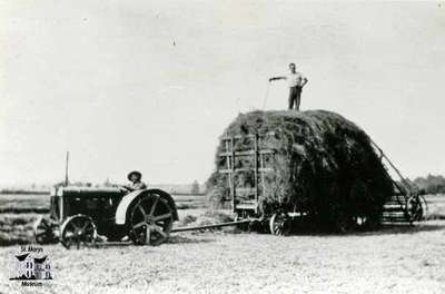 Boy driving tractor pulling a load of hay