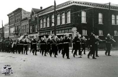 Parade passing Northwest Corner of Queen and Wellington Streets