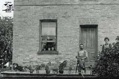 Detail of couple with dog on front porch of brick home