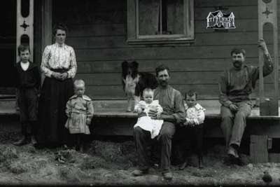 Detail from Ornate frame house, view of front & porch with family grouping, farm dog