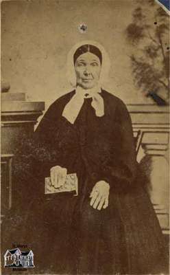 Elderly woman seated, holding a book