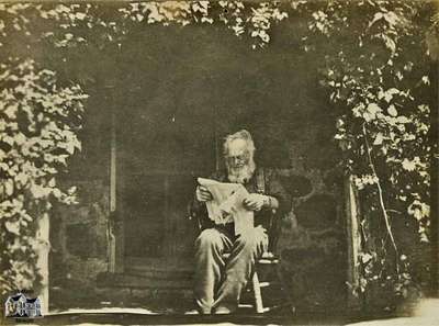 Elderly man seated; reading paper