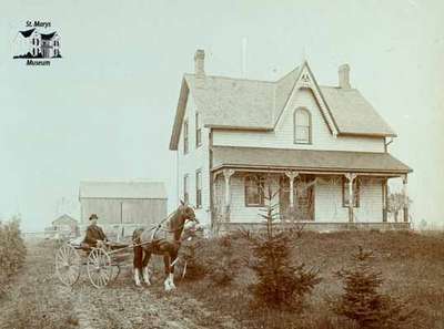 House, barn, man with horse and buggy.