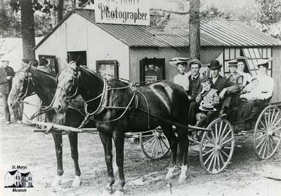 Buggy full of people posed in front of a photo studio building