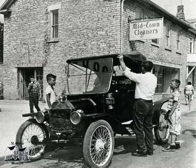 Man adjusting top on vintage car on Wellington Street