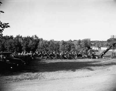 Unidentified Man Poses for a Photo Surrounded by Agricultural Implements