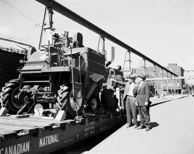 Loading an IHC McCormick model 91 self-propelled combine onto a flatbed railroad car.