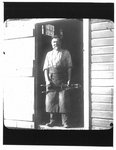 Portrait of blacksmith holding a tool, standing in a doorway.